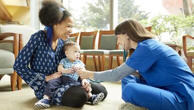 mom and baby and visiting person sitting on floor