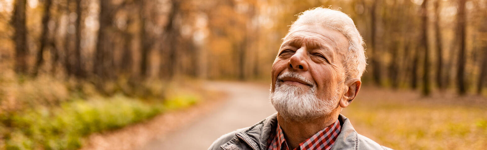 An older man taking a deep breath in autumn