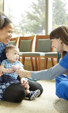 mom and baby and visiting person sitting on floor