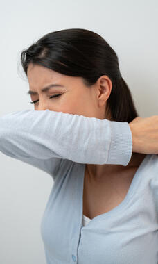 person sneezing into arm
