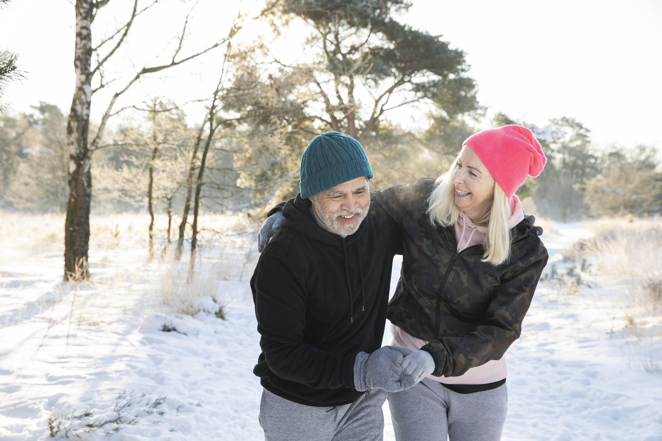 Two people with arms around each other, walking in the snow. 
