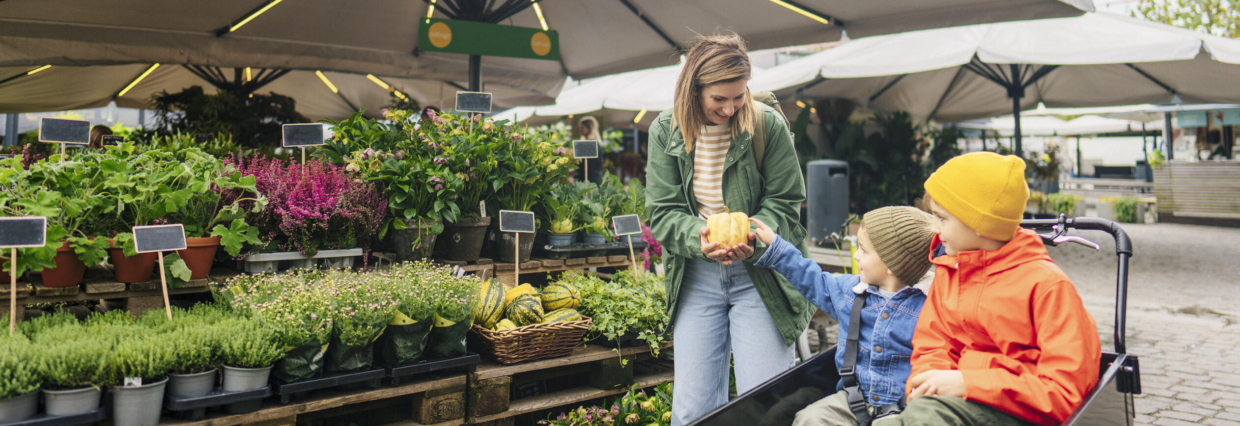 A mother showing her children a squash at a garden store.