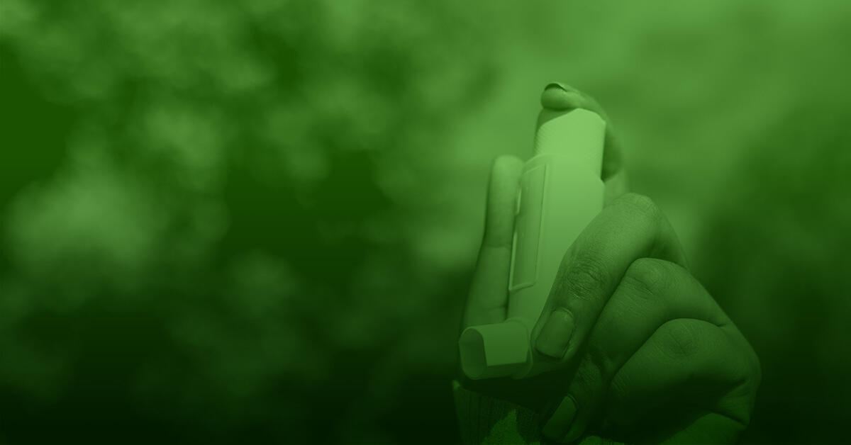 A hand holding an asthma inhaler.