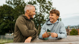 A parent talking with their teen outdoors, both smiling