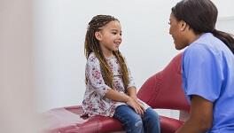 Dental hygienist talking with school aged girl.