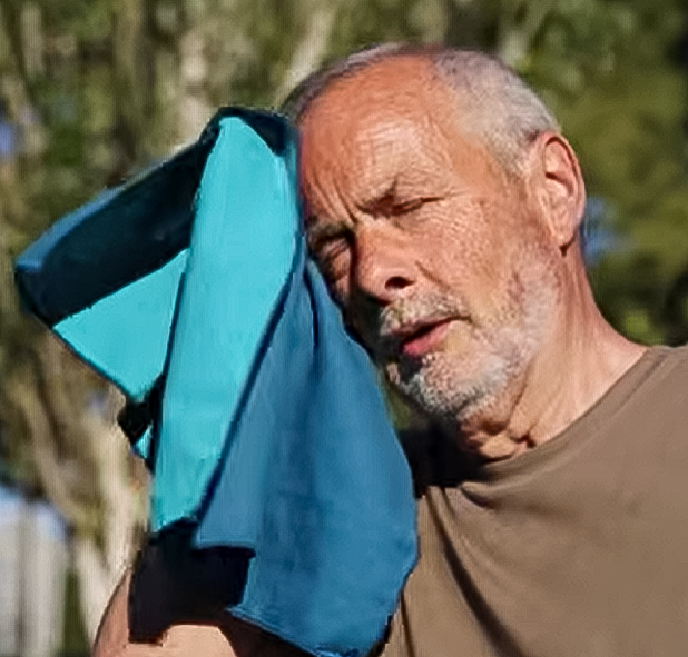 Older man wiping sweat off his forehead with a towel.