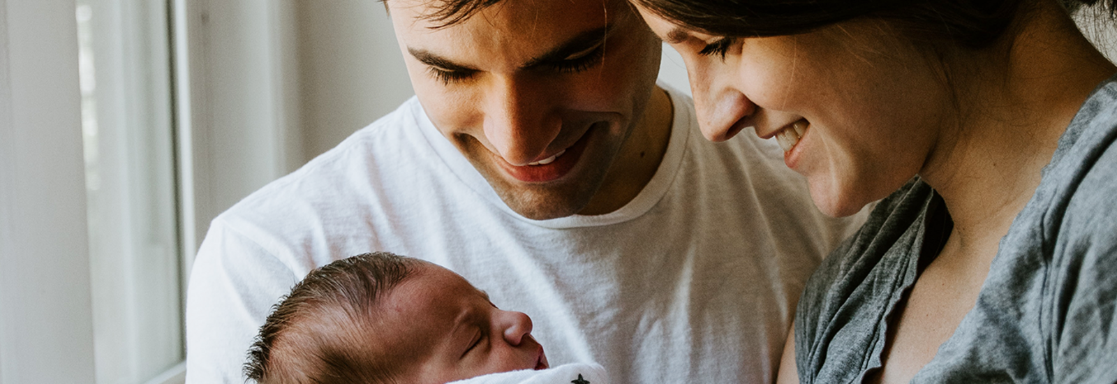 parents smiling at newborn baby