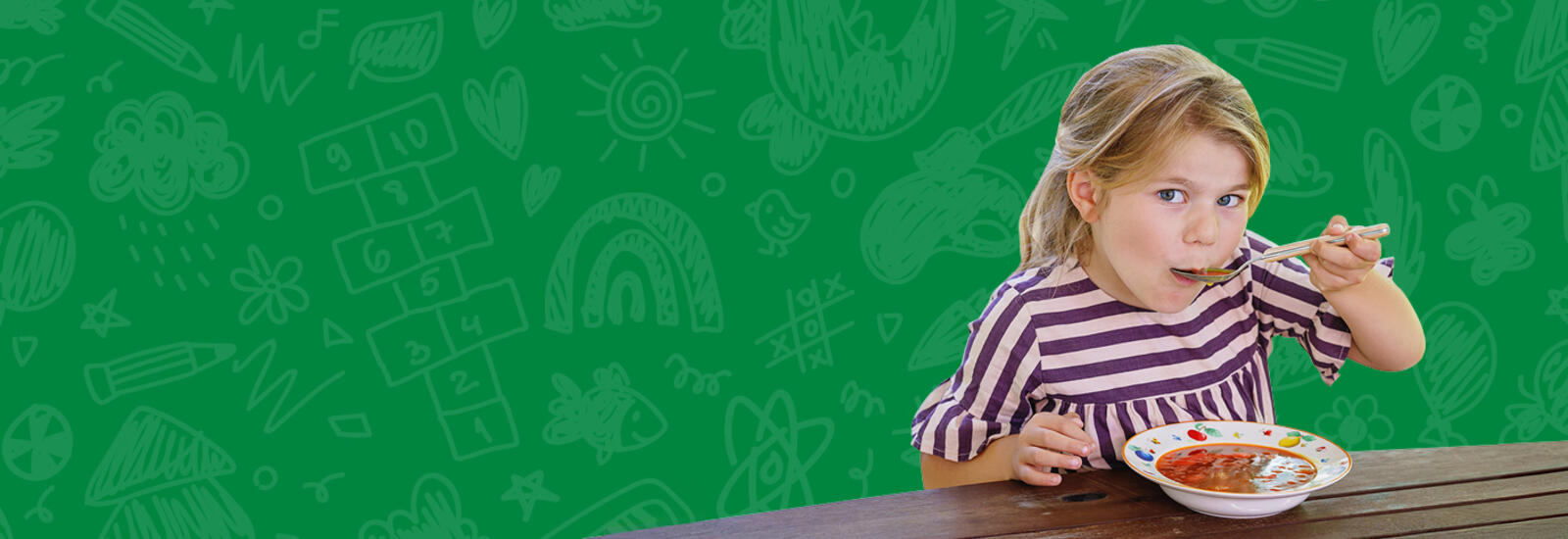 Child eating soup with a green background