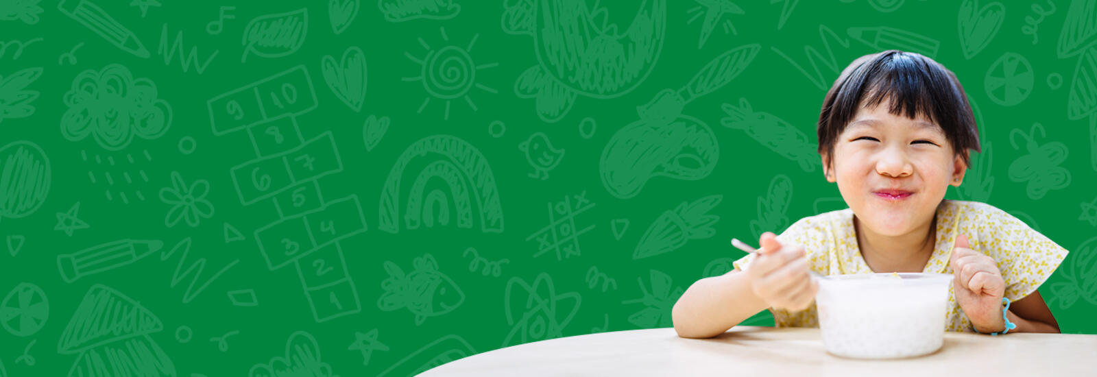 Child eating soup from a bowl with a green background