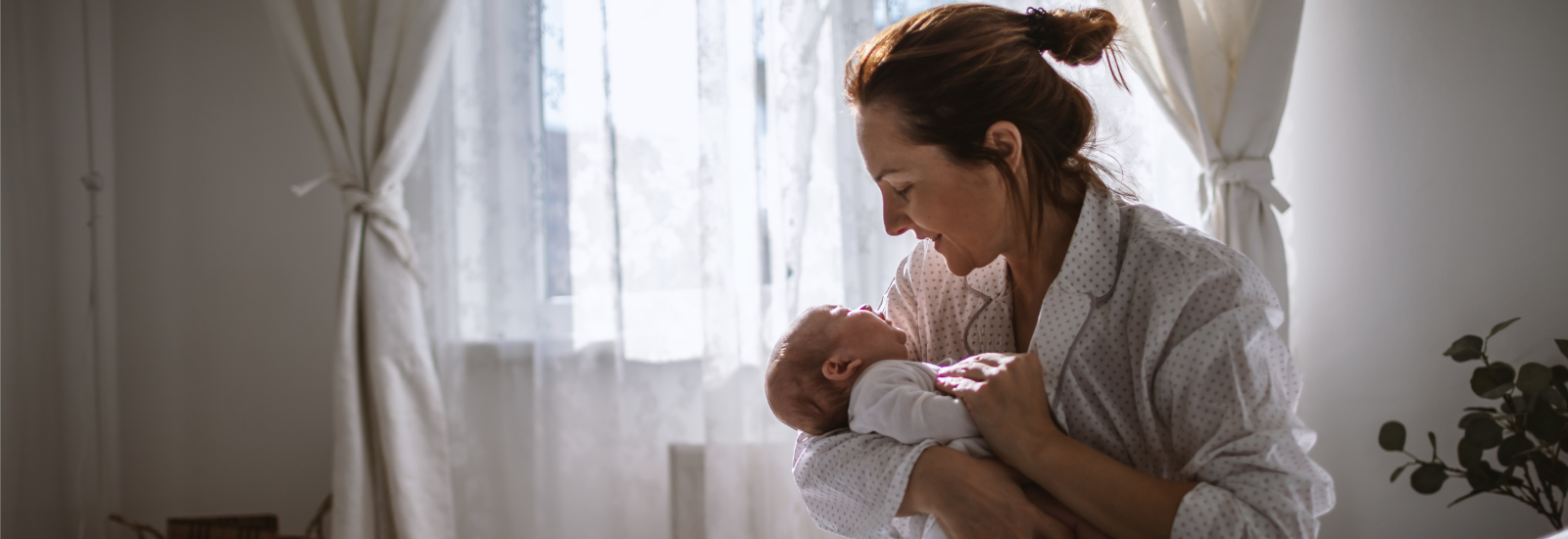 A parent holding and looking at their baby. 