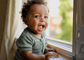 A toddler holding onto a windowsill.