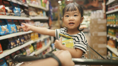 child pointing at supermarket shelf