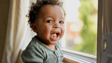A toddler holding onto a windowsill.